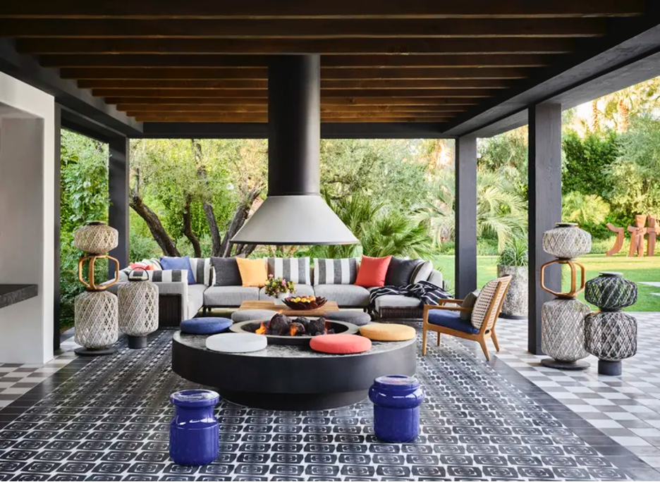 covered outdoor patio with graphic tile flooring, a fire pit, sofa, and lanterns