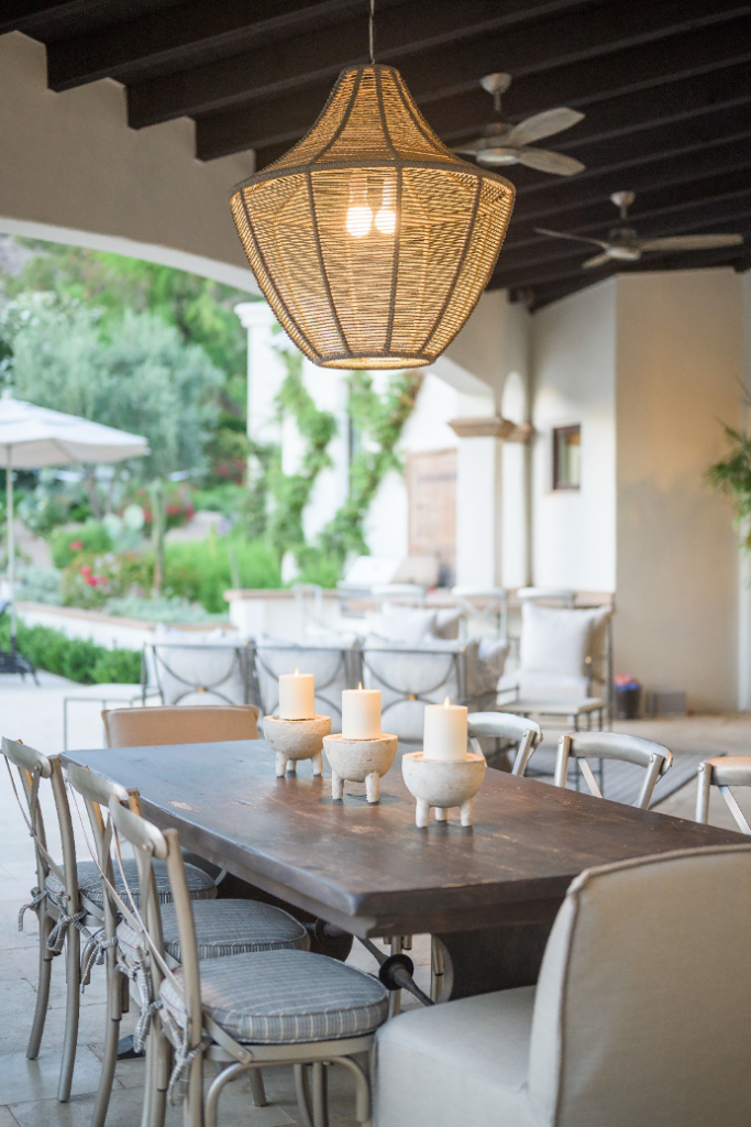 covered patio with dining table illuminated by candles and overhead pendant light