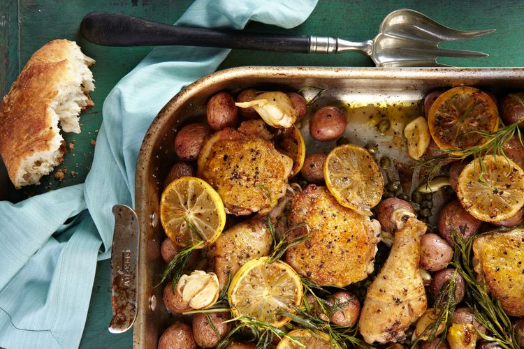 Lemon rosemary garlic chicken and red potatoes in one-pan dish with serving fork and bread