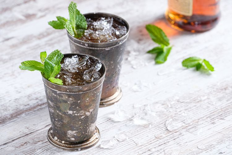 two mint juleps in silver cups and ice and fresh mint sprigs
