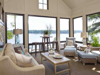 Sunroom of home on Reeds Lake in East Grand Rapids, MI, with upholstered seating, cushioned wicker seating, lake views, neutral decor, and a Jack Russell terrier