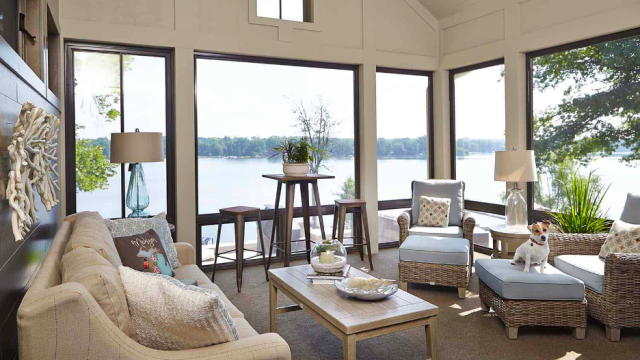Sunroom of home on Reeds Lake in East Grand Rapids, MI, with upholstered seating, cushioned wicker seating, lake views, neutral decor, and a Jack Russell terrier