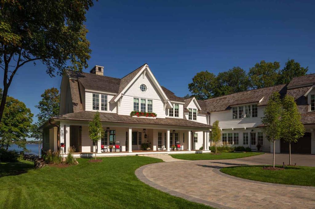 farm house style lake home with pvc column wraps on front porch to enhance architectural design; brick paved motorcourt in foreground