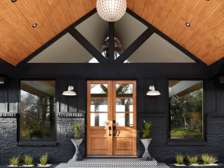 Contemporary front porch design with vaulted roof, slatted wood ceiling, natural stained wood doors, planters, greenery, decorative tile stair platform for Oregon lake home