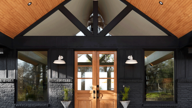 Contemporary front porch design with vaulted roof, slatted wood ceiling, natural stained wood doors, planters, greenery, decorative tile stair platform for Oregon lake home