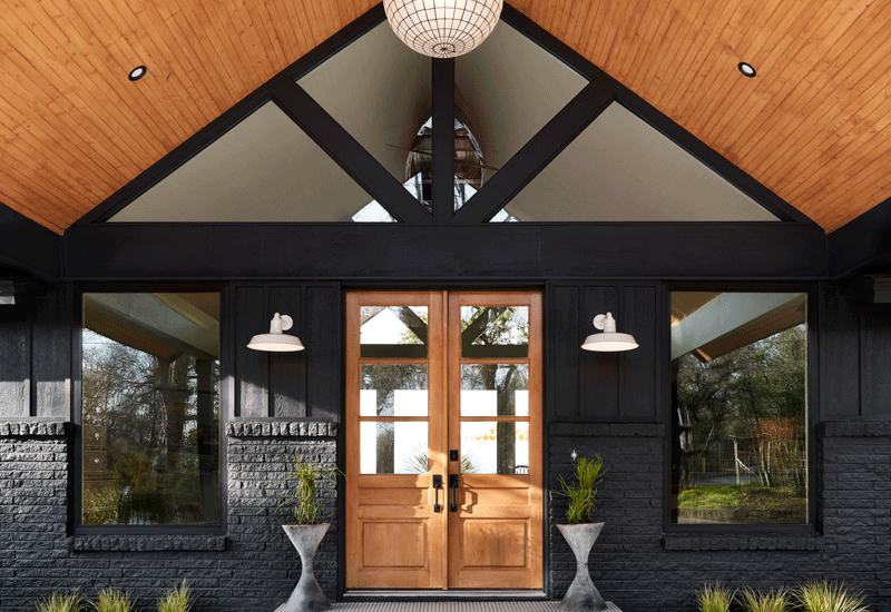 Contemporary front porch design with vaulted roof, slatted wood ceiling, natural stained wood doors, planters, greenery, decorative tile stair platform for Oregon lake home