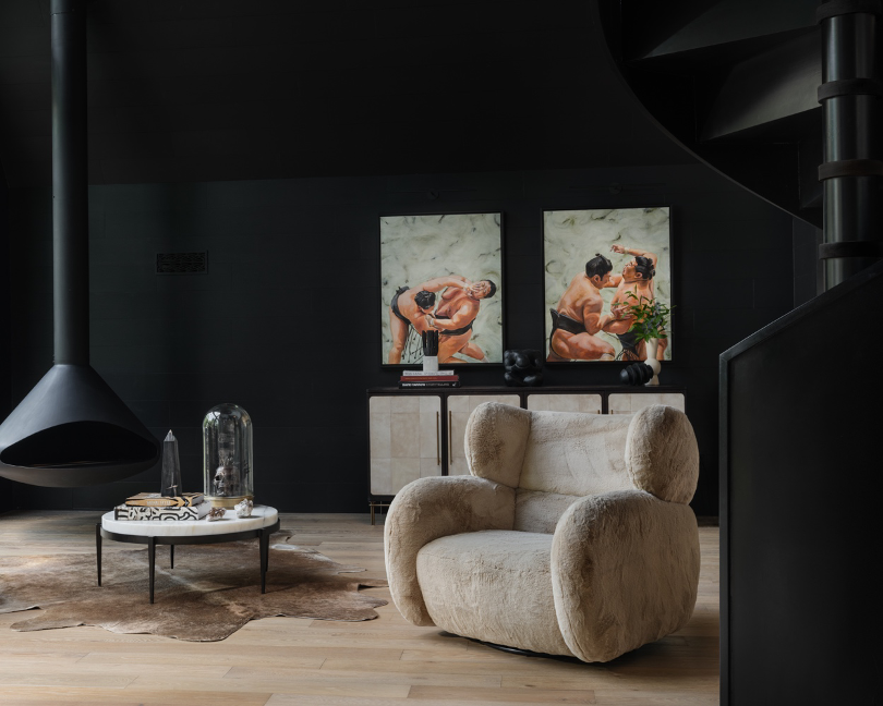 Living room hanging fireplace and a pair of sumo-wrestler paintings in background. Lounge chair and cocktail table and console