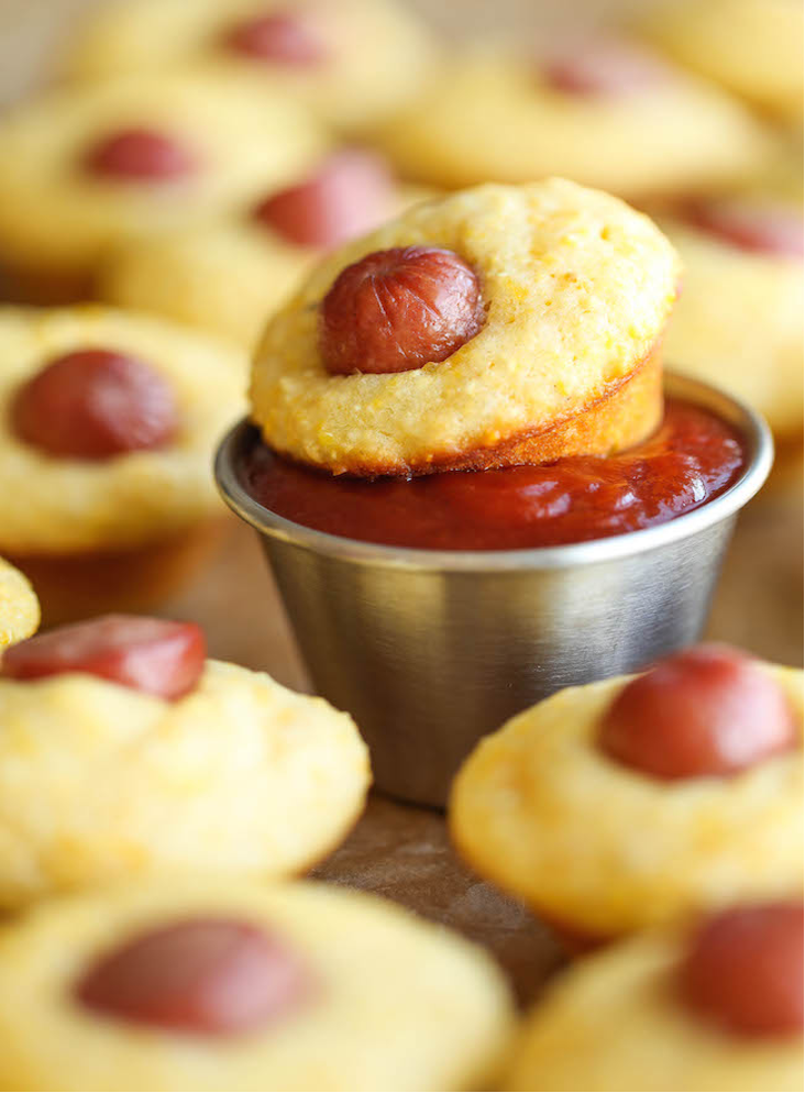 Mini Corn Dog Muffins with one dipped in a metal ramekin of ketchup