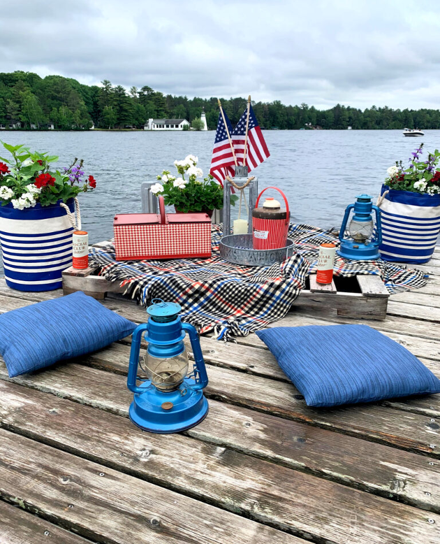 picnic spread for the 4th of July on a dock on the lake with boat in background
