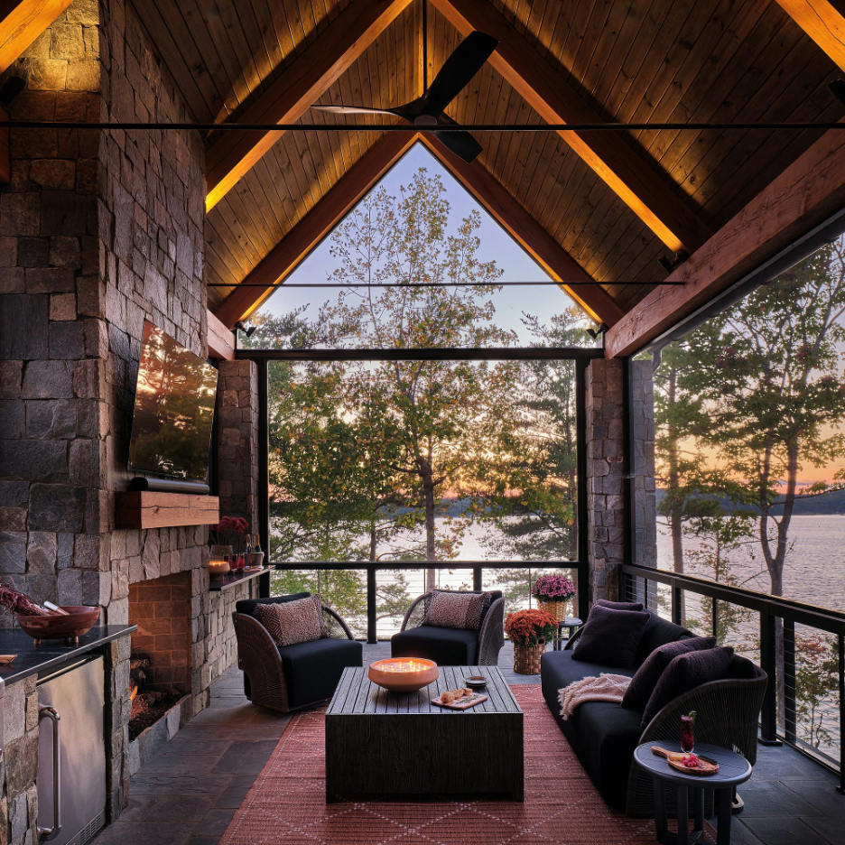breathtaking all-season covered porch overlooking lake at sunset, mountains, with comfy seating, TV, fireplace, bar station, storage cocktail table, patterned rug