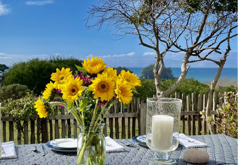 Beautiful outdoor table scape with a vase of sunflowers and a vast lake landscape and lake in background