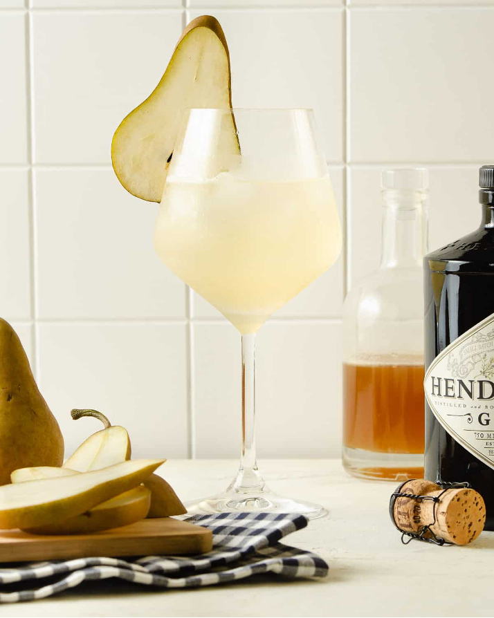 Honey Ginger Gin and Prosecco Cocktail in a stemmed wine glass with a pear garnish
