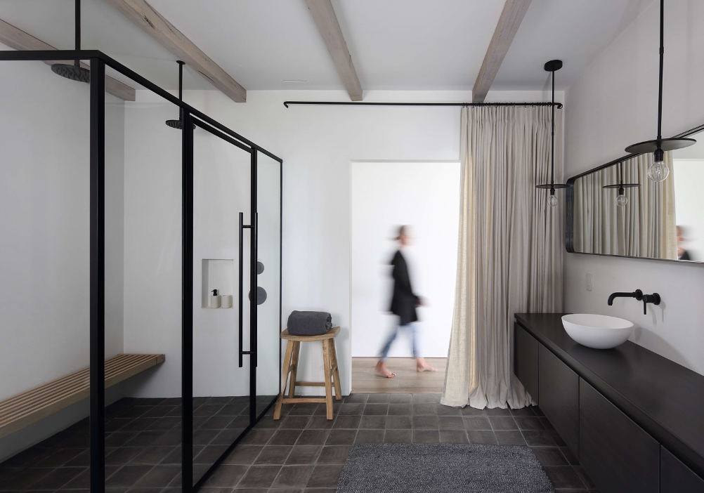 The high-contrast black and white aesthetic is reiterated in the master bathroom with a generous double walk-in shower and a massive black vanity topped with a bright white sink.