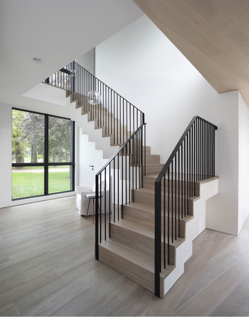An elegant staircase outfitted in white oak risers and accented with a black railing appears to float weightlessly to the second story, where the children’s bedrooms offer spectacular views of the lake.