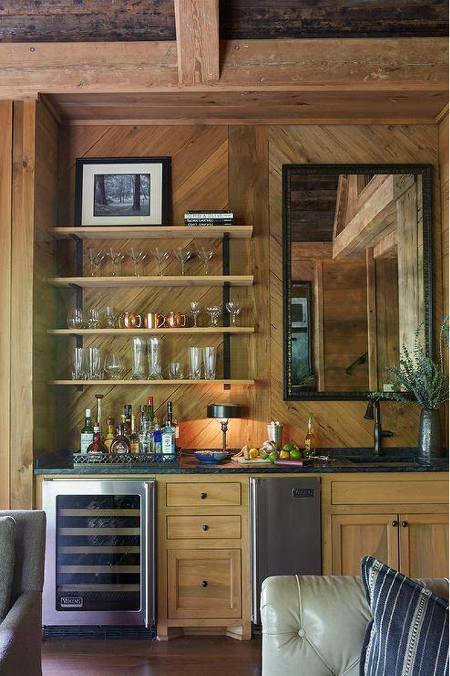 Rustic-style wet bar incorporated into a lake home with rustic woods, open shelves, stone countertop, and refrigeration and storage below.