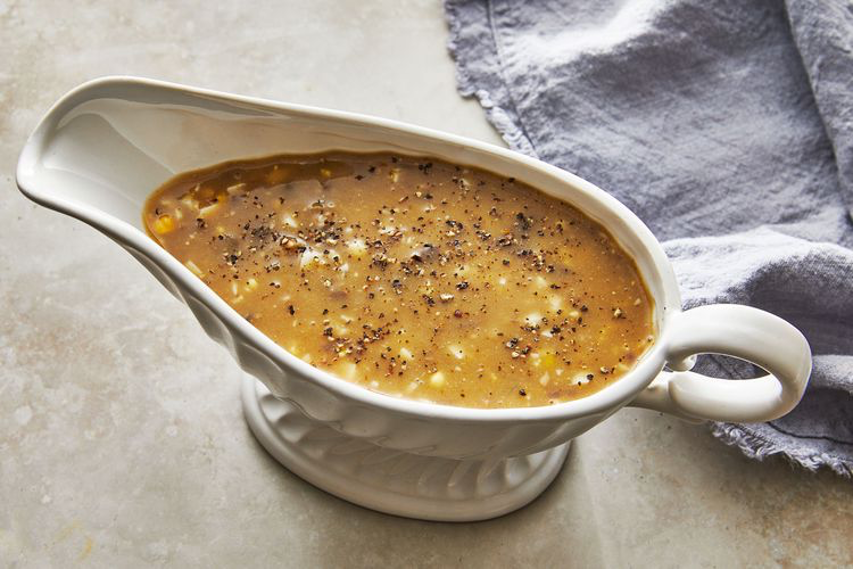 Giblet Gravy in a gravy boat on the able with a crumpled linen napkin