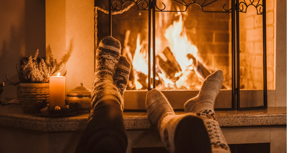 cozy socks on propped feet in front of a roaring fireplace
