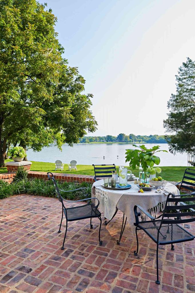 Small brick patio with a dining table that seats 4 with a lake background