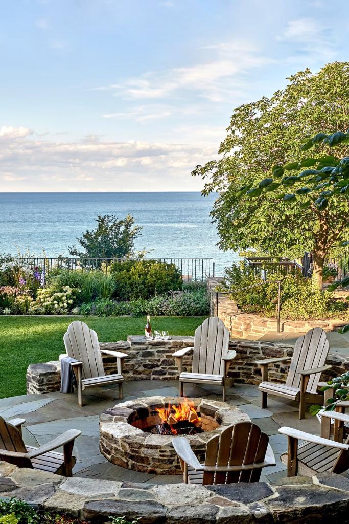Elevated firepit area with stone retaining wall, stone slab foundation, and circular stone fire pit on Lake Michicgan

