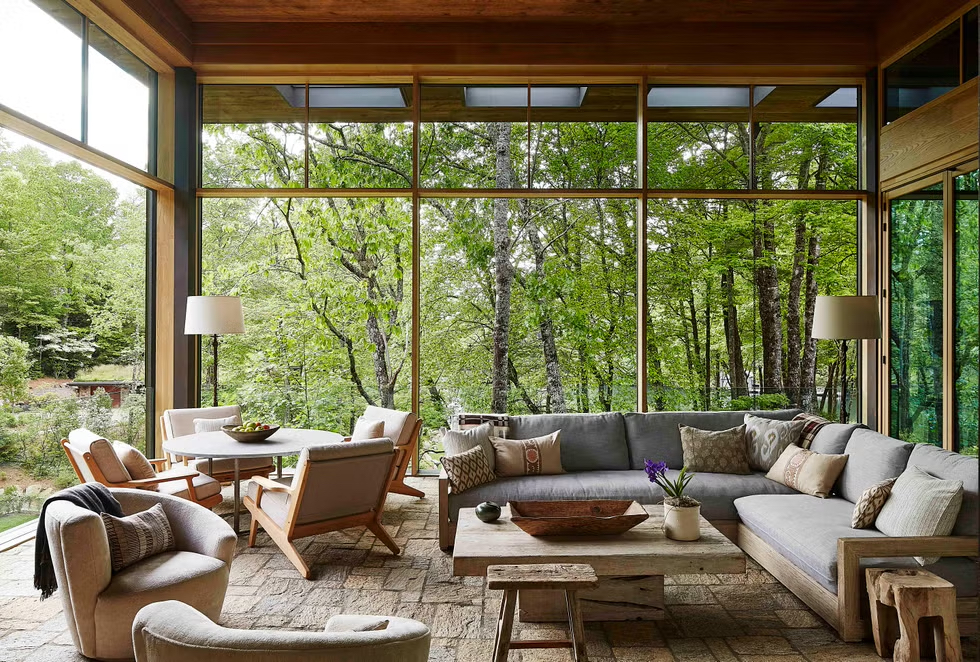 A flagstone and oak terrace is designed with retractable screens to immerse the refined sitting area in the mountain and lake landscape of a Lake Toxaway, NC lodge
