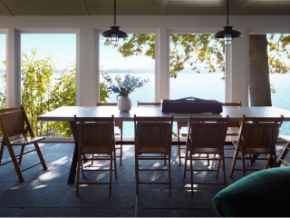 summer porch at a Maine lake home with dining table and chairs overlooking the water and landscape