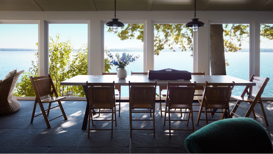 summer porch at a Maine lake home with dining table and chairs overlooking the water and landscape
