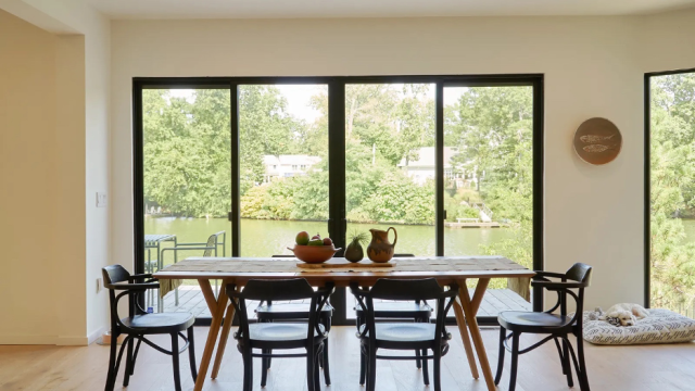 Japandi-style dining area in front of a wide glass expanse overlooking a lake