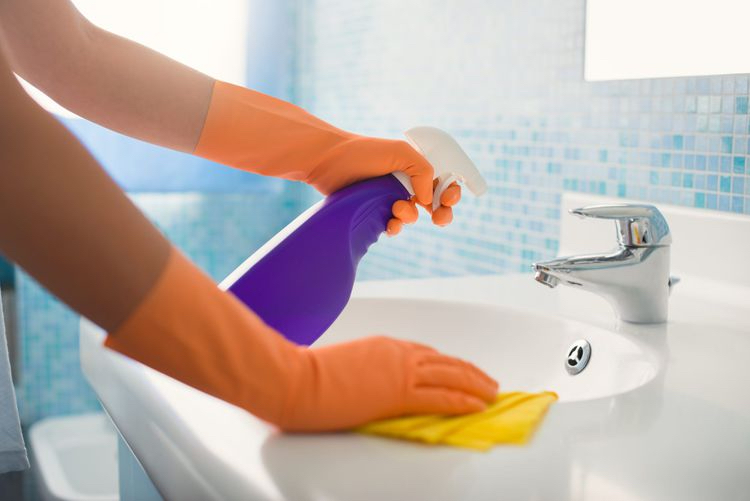 cleaning a bathroom sink, faucet, and countertop